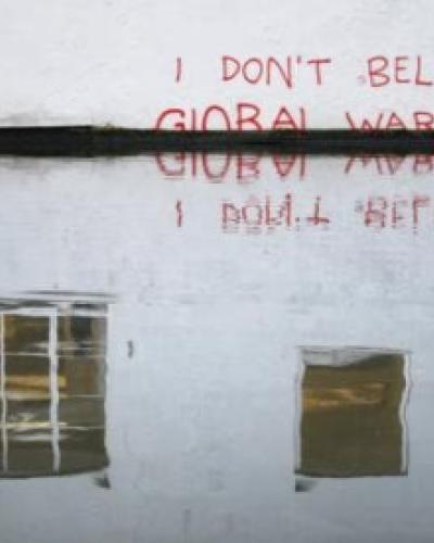 flooding with spray paint on wall "I don't believe in global warming"