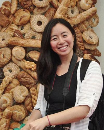 Annie Sheng poses in front of a bread/bagel display